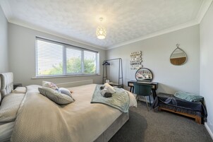 Un dormitorio con cama, escritorio, silla, espejo y ventana con persianas.