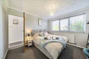 A bedroom with a bed, bedside table, lamp, window, radiator, and a door. - 2 Bed - Sleeps 4 - Parking - Pet Friendly (Filey)