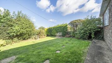 A well-maintained backyard with a grassy lawn, a stone pathway, and a brick wall.