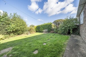 Un jardín trasero cuidado con césped, piedras y un muro de ladrillo.
