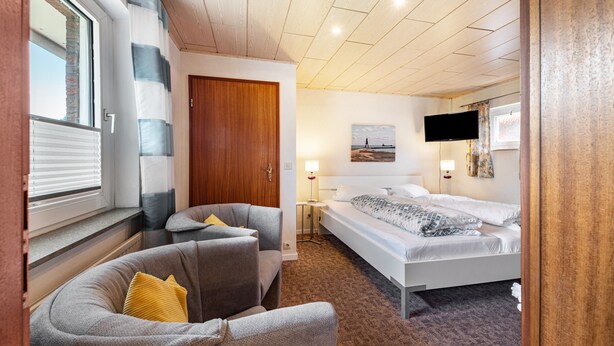 Een hotelkamer met een bed, een bank, een televisie en een raam met zonwering.