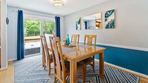 A dining area with a wooden table and chairs, a blue accent wall, and a view of the outdoors.