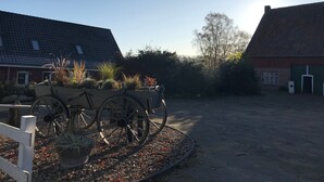 A rural setting with a wooden cart, gravel path, and buildings with tiled roofs.