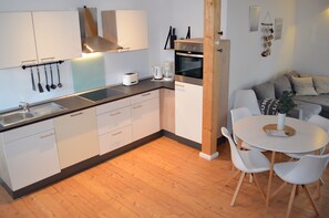 A modern kitchen with white cabinets, a built-in oven, and a coffee maker.