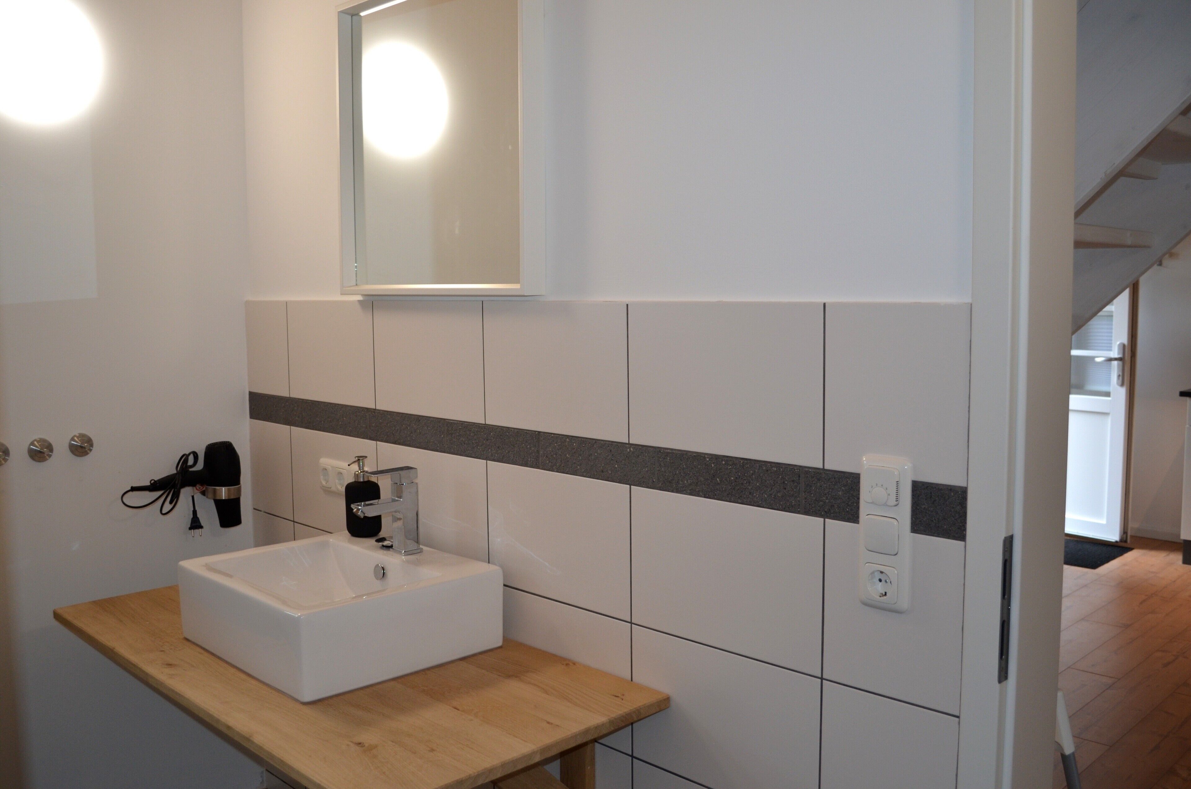 Een badkamer met een witte wasbak, spiegel en handdoekhouder.
