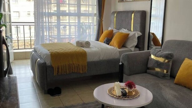 A modern bedroom with a bed, a sofa, a round table, and a large window.