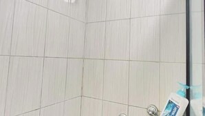 A bathroom with white tiles and a hand soap dispenser on the wall.