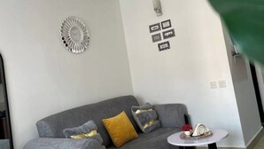 A modern living room with a grey sofa, decorative wall art, and a small round table with a decorative item.