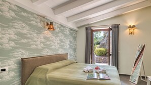 A bedroom with a bed, a bedside table, a wall with a cloud mural, a window with curtains, and a painting on the wall. - Villa Belvedere Condor - L - with Pool (Alassio)
