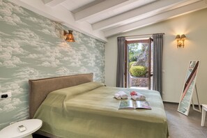 A bedroom with a bed, a bedside table, a wall with a cloud mural, a window with curtains, and a painting on the wall. - Villa Belvedere Condor - L - with Pool (Alassio)