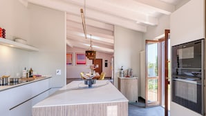 A modern kitchen with a large island, a dining area with a table and chairs, and a view to the outside. - Villa Belvedere Condor - L - with Pool (Alassio)