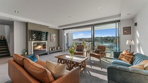Ein modernes Wohnzimmer mit Kamin, bequemen Sitzmöglichkeiten und einem großen Fenster mit Blick auf die Stadt.
