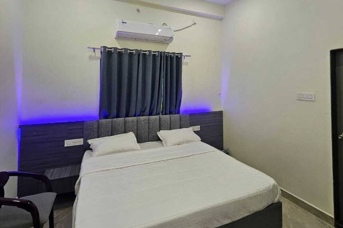 A bedroom with a bed, a ceiling fan, an air conditioning unit, and a curtain.