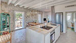 A spacious kitchen with a large island, stone walls, and a view to the outside.