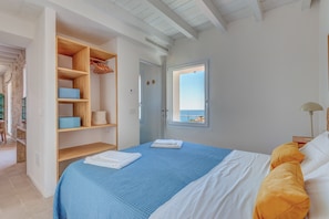 Une chambre à coucher avec un lit, une armoire en bois, une fenêtre donnant sur un beau paysage et une porte.