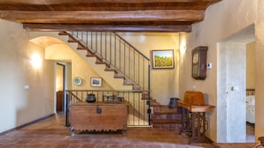 Ein rustikales Interieur mit einer Holztreppe, einer hölzernen Bank und einer an der Wand befestigten Uhr.