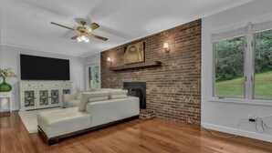 Ein Wohnzimmer mit Backsteinwand, Kamin, weißem Sofa und Deckenventilator.