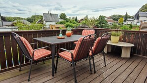 Une terrasse avec une table et des chaises, entourée d’une clôture en bois.