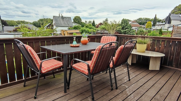En terrasse med et bord og stole, omgivet af et træhegn.