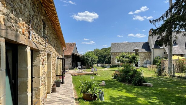 A stone building with a wooden deck and a grassy yard. - Guesthouse near La Flèche - Pets Allowed - Breakfast Included (Bazouges Cré sur Loir)