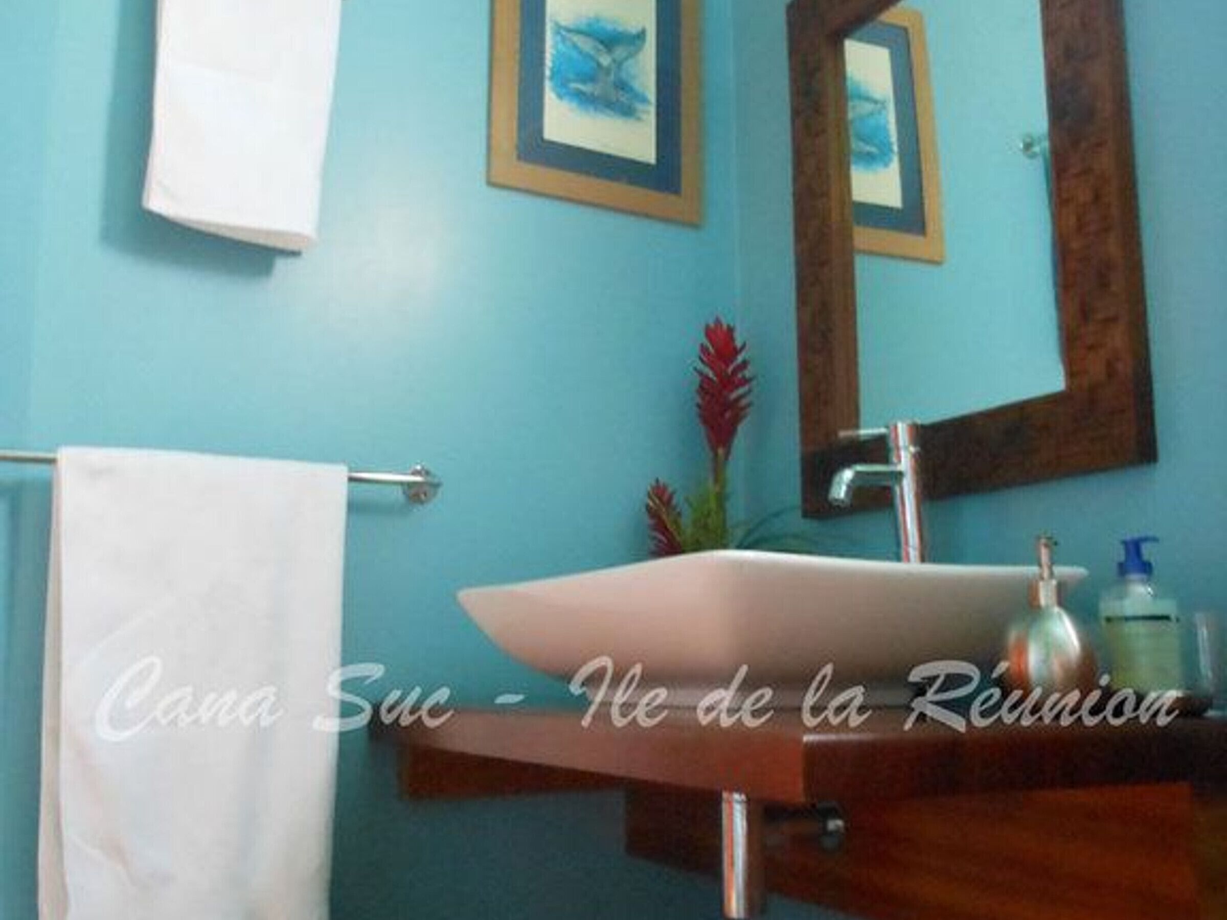 A bathroom with a white sink, a mirror, and a towel hanging on a rack.