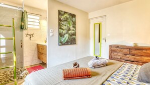 A bedroom with a bed, a wooden dresser, a mirror, and a door. - Comfortable apartment with terrace and direct pool access (La Possession)