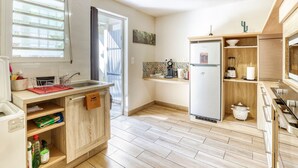 A compact kitchen with a built-in sink, a refrigerator, and a stove. - Comfortable apartment with terrace and direct pool access (La Possession)