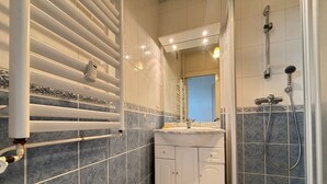 A bathroom with a shower, a sink, and a radiator. - Studio sea view and balcony, 10th floor (Les Sables-d'Olonne)