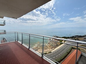 Un balcon avec vue sur la mer, une route et un paysage rocheux.