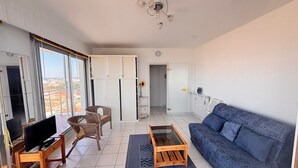 A living room with a sofa, a coffee table, a TV, and a chair. - Studio sea view and balcony, 10th floor (Les Sables-d'Olonne)