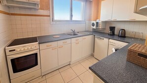 A kitchen with a stove, oven, microwave, sink, and cabinets. - Studio sea view and balcony, 10th floor (Les Sables-d'Olonne)