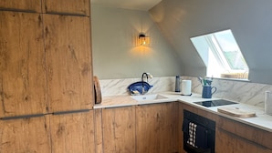 Una cocina con armarios de madera, encimera de mármol, pileta, estufa y ventana con vistas.
