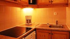 Una cocina con armarios de madera, cafetera, lavavajillas y un lavabo.