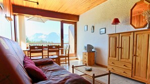 A cozy living area with a sofa, wooden cabinets, and a dining table. - Studio for 4 people at the foot of the slopes near shops (Chamrousse)