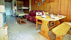 A cozy room with a bunk bed, a sofa, a dining table with chairs, and a television. - Studio for 4 people at the foot of the slopes near shops (Chamrousse)