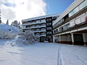 Ein mehrstöckiges Hotel mit verschneiter Fassade und Parkplatz.