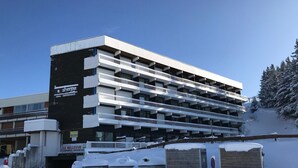 A multi-story parking garage with a sign for 'Sherpa Supermarché' on the left. - Cozy 19m² studio at the foot of the slopes with pool (Chamrousse)