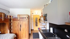 A compact room with a bunk bed, a kitchenette with a microwave, and a small bathroom. - Cozy 19m² studio at the foot of the slopes with pool (Chamrousse)
