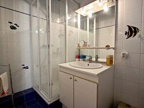 A bathroom with a glass shower enclosure, a white sink with a mirror above it, and a towel rack. - Lovely apartment at the foot of the slopes, cozy and bright (Chamrousse)