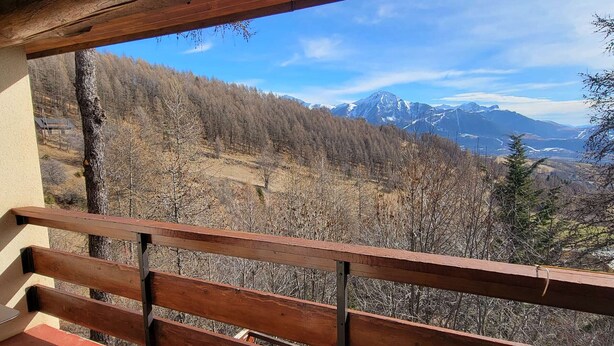 Un balcón de madera con vistas a un paisaje montañoso.