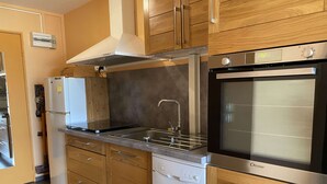 A modern kitchen with wooden cabinets, a stainless steel sink, a dishwasher, and a built-in oven.