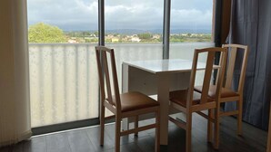 A balcony with a table and two chairs, overlooking a landscape with buildings and trees.