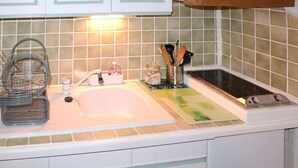 Una cocina con un lavamanos, un escurreplatos, un dispensador de jabón y una especiero.
