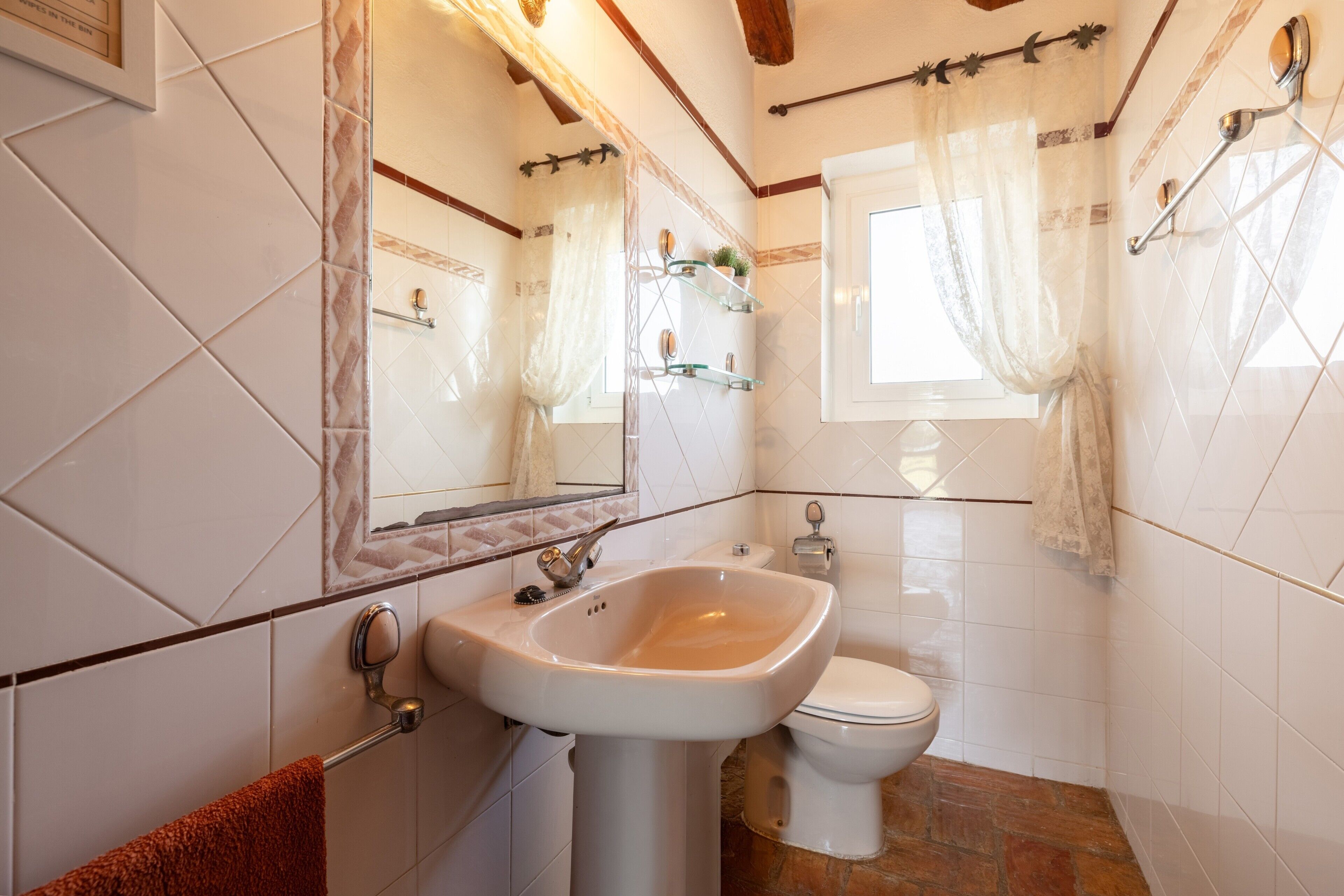 A bathroom with a sink, toilet, and a mirror.