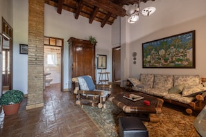 A spacious living room with a wooden coffee table, a sofa, and a large painting on the wall.