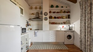 A compact kitchen with white cabinets, a microwave, a stove, a sink, and a washing machine. - Apartment in Holiday Home "Casa Sorrapa" (Deltebre)