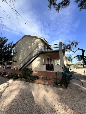 A building with a staircase leading to a covered area, surrounded by gravel and plants. - Apartment in Holiday Home "Casa Sorrapa" (Deltebre)