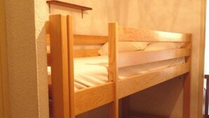 A bunk bed in a room with a wooden headboard and a shelf above it.