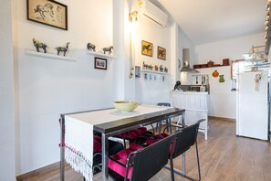 Un coin repas avec une table, des chaises et un réfrigérateur blanc en arrière-plan.