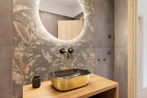 Une salle de bain avec un lavabo sur colonne, un meuble-lavabo en bois et un grand miroir.